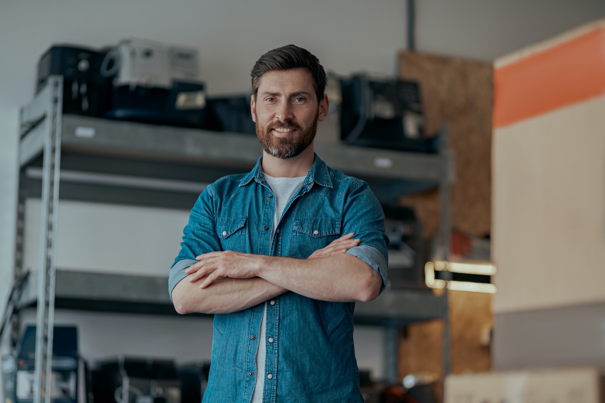Portrait of business owner standing on workshop of coffee machines warehouse