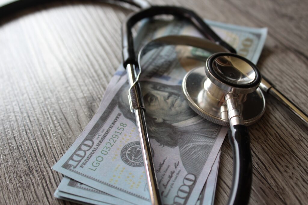 Stethoscope and money on wooden table.