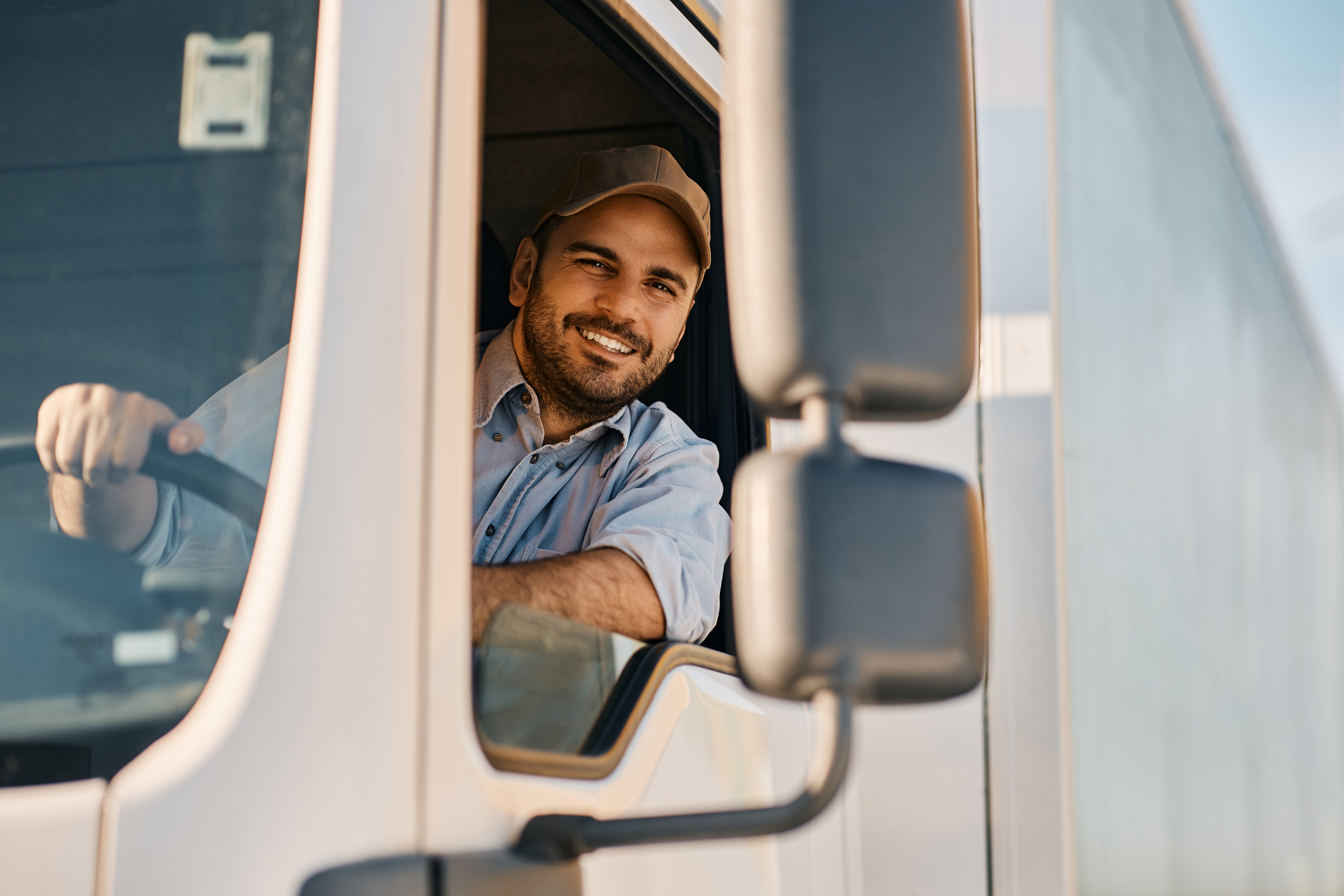 happy truck driver looking through side window while driving his truck  - Blog