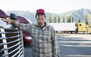caucasian man truck driver with his truck parked in a lot at a truck stop  300x187 - Small Business Dictionary: Holdback