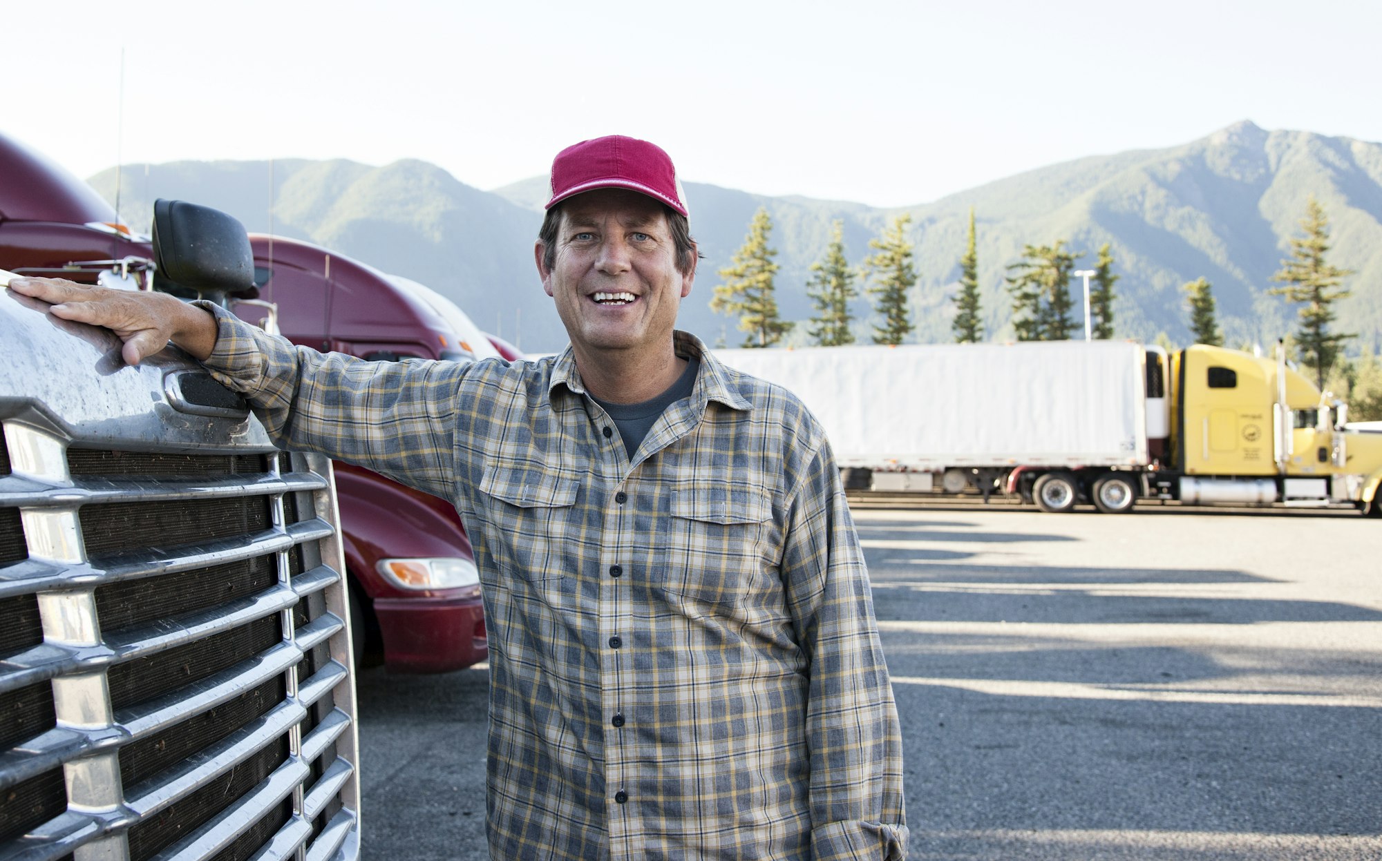 caucasian man truck driver with his truck parked in a lot at a truck stop  - Blog