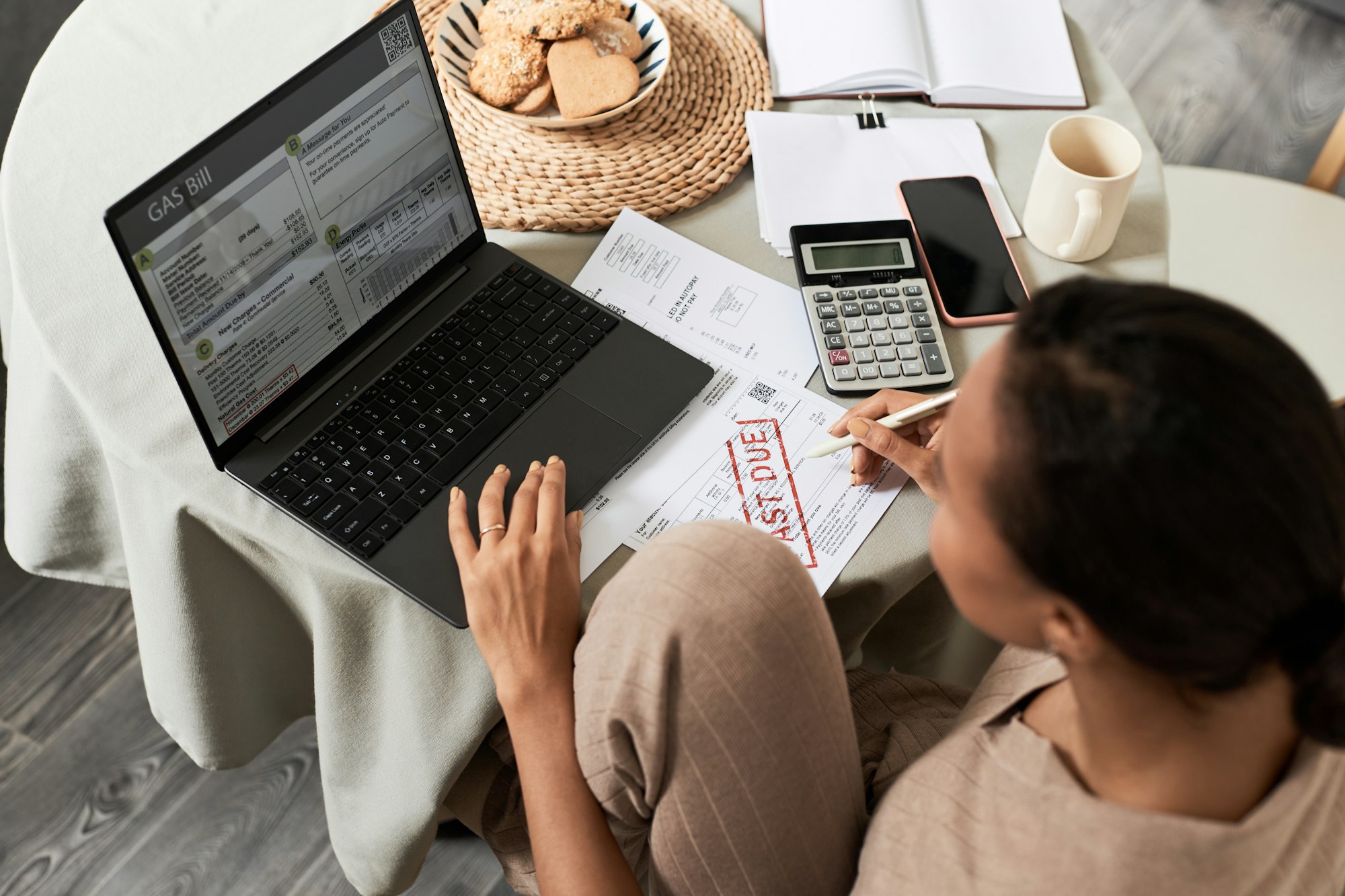 Black young woman doing taxes at home and using laptop