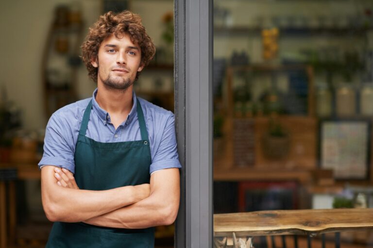 Hes a proud shop owner. A handsome young store owner standing in the entrance of his shop.